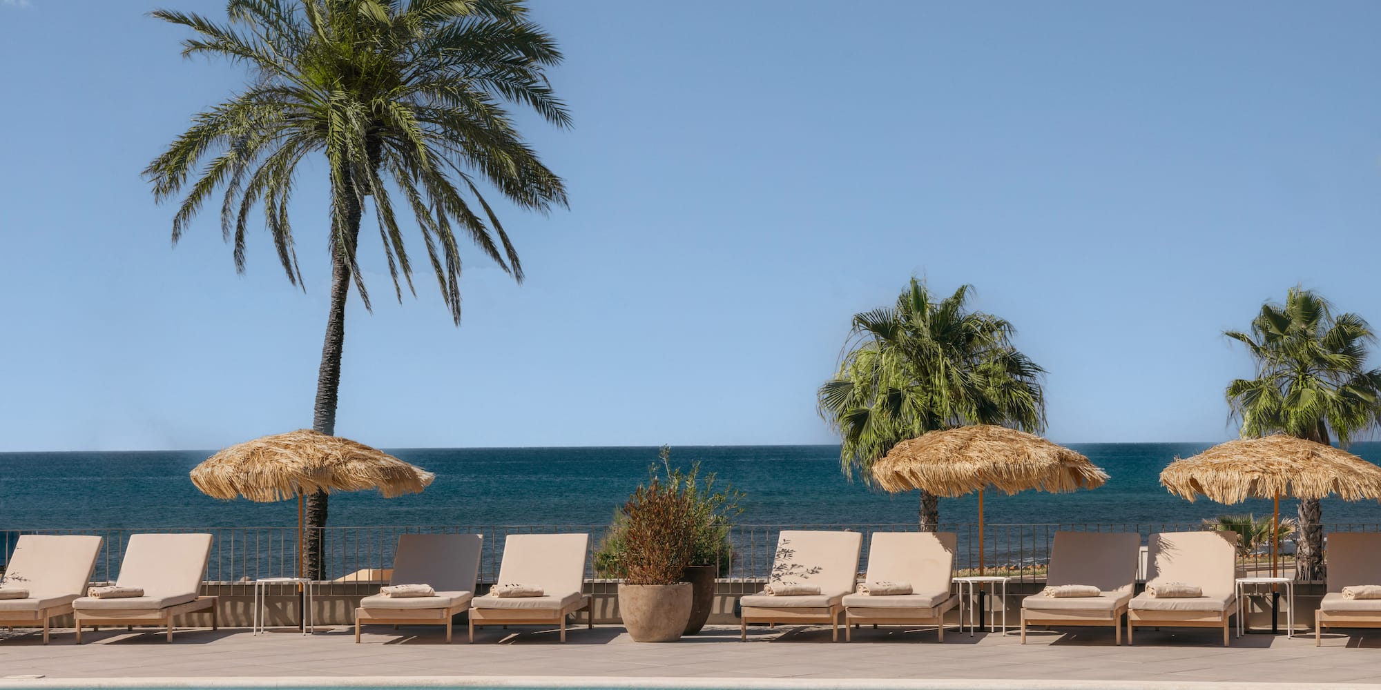 a pool with chairs and umbrellas by the water