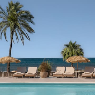 a pool with chairs and umbrellas by the water