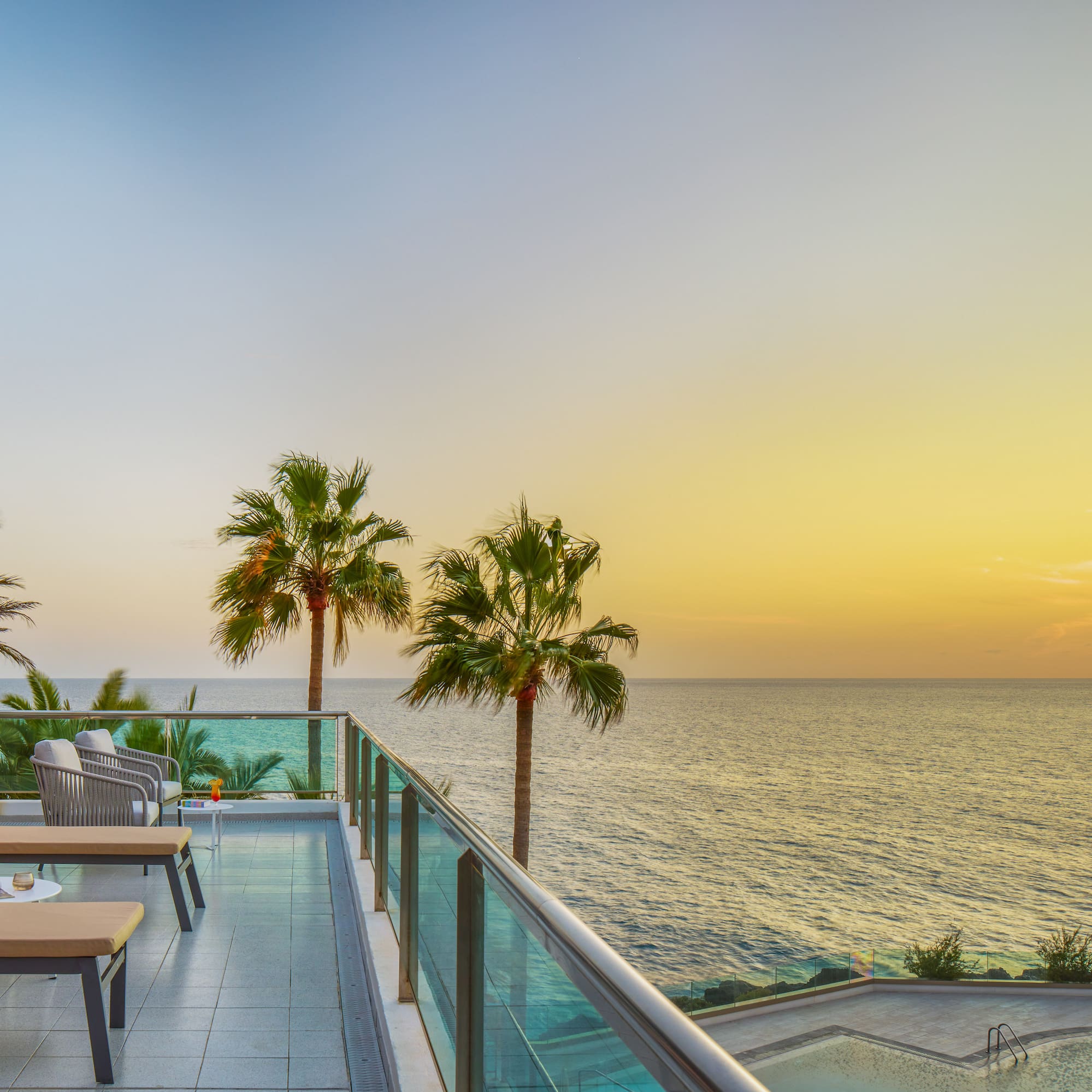 a deck with chairs and a pool overlooking the ocean