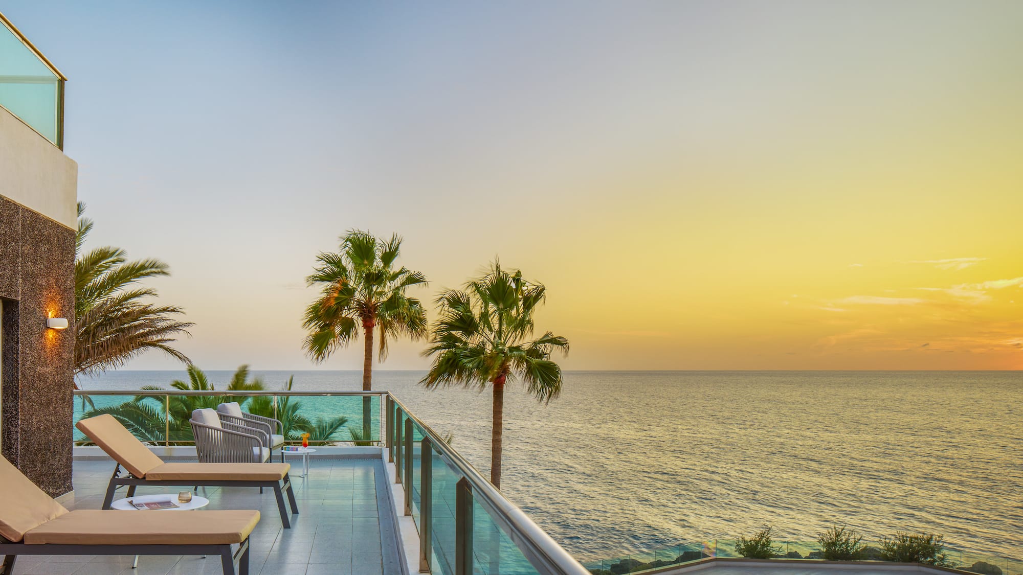 a deck with chairs and a pool overlooking the ocean