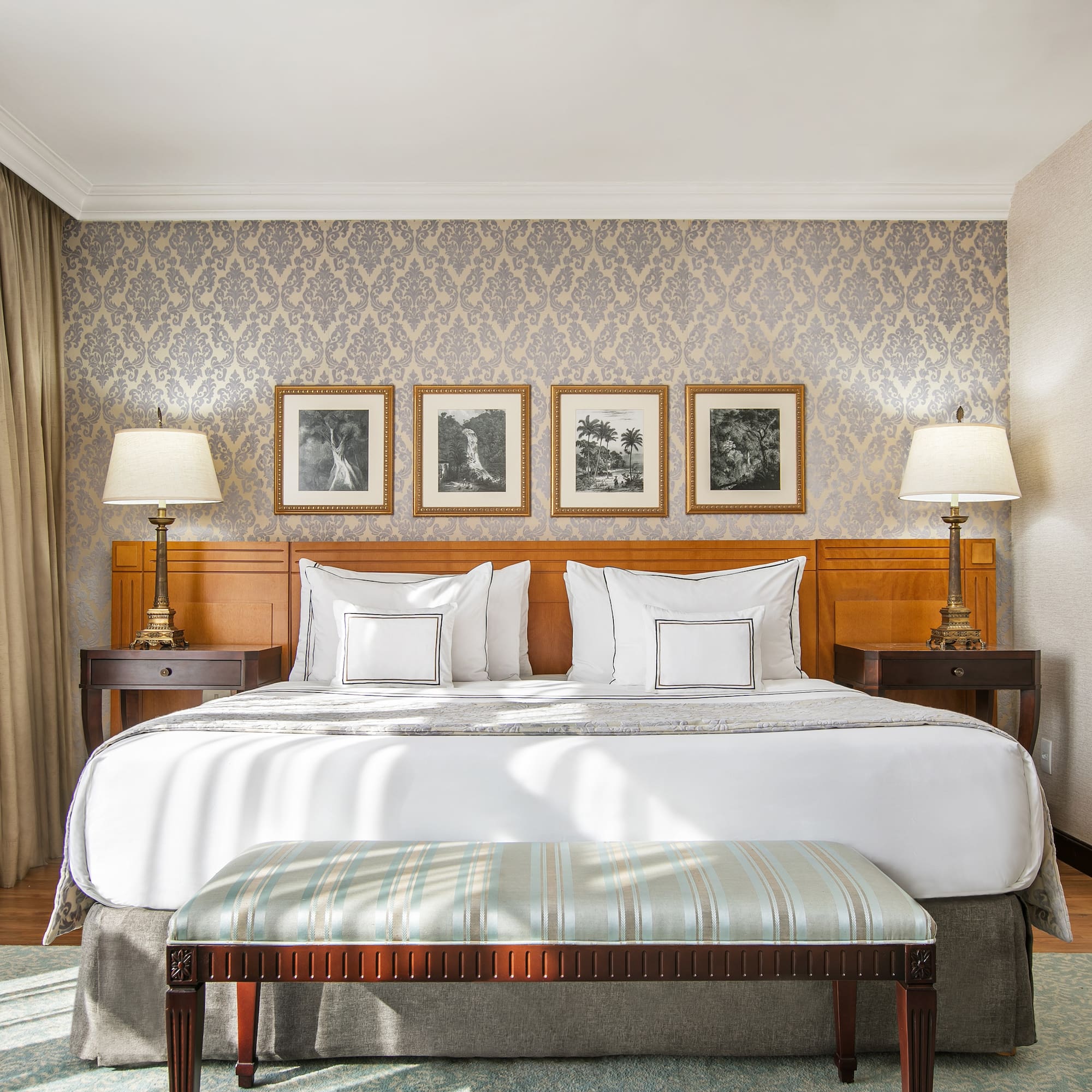 a bed with lamps and a bench in a room