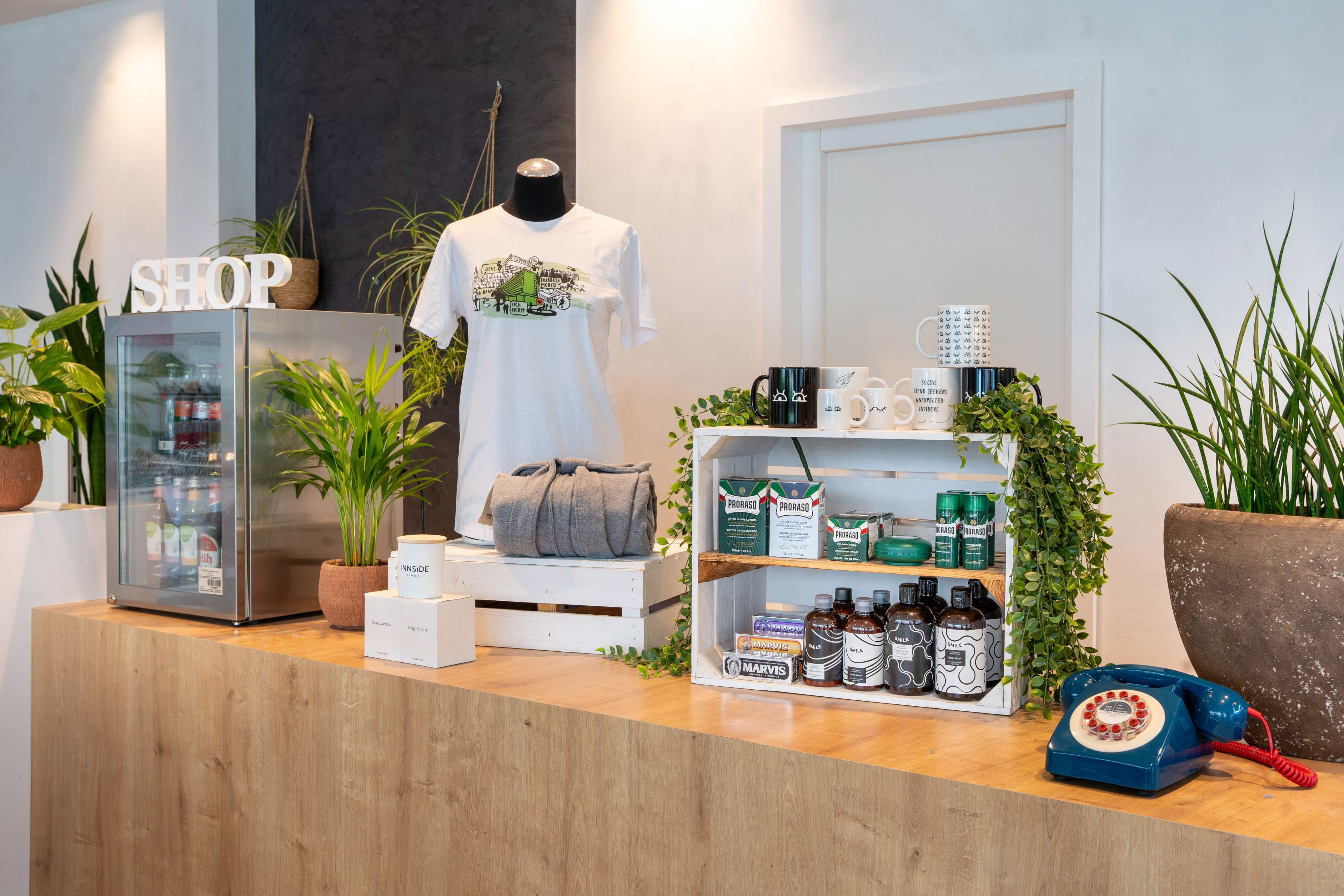 Shop display: branded t-shirt, Proraso, Marvis, drinks, plants, retro phone.