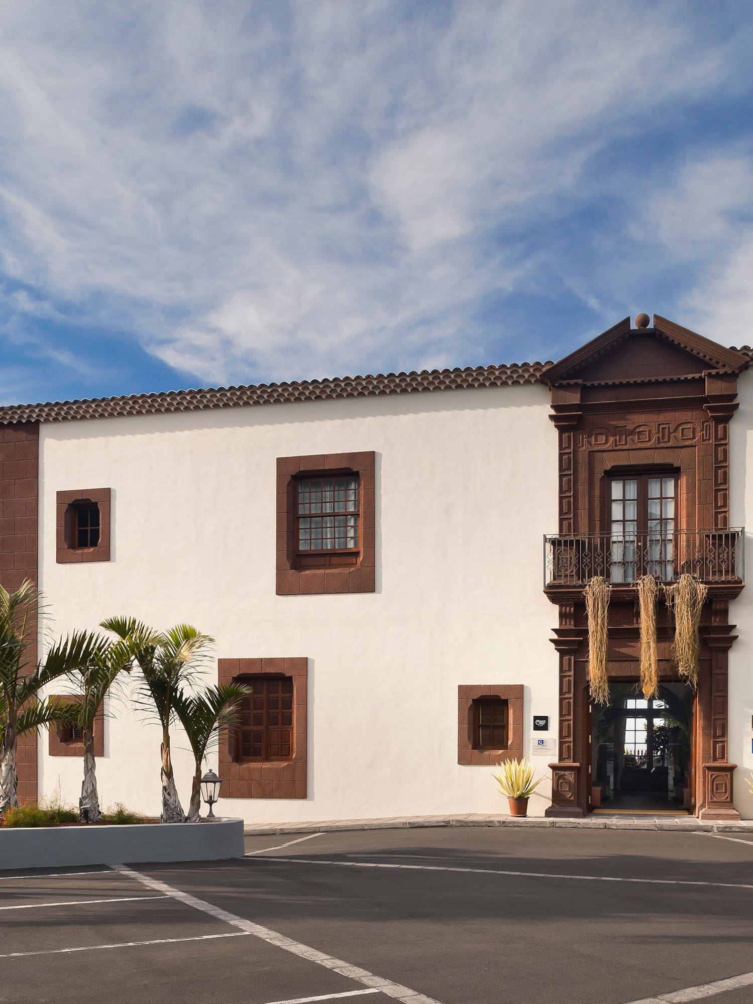 Historic hotel with bell tower, palm trees, and ornate brown facade.