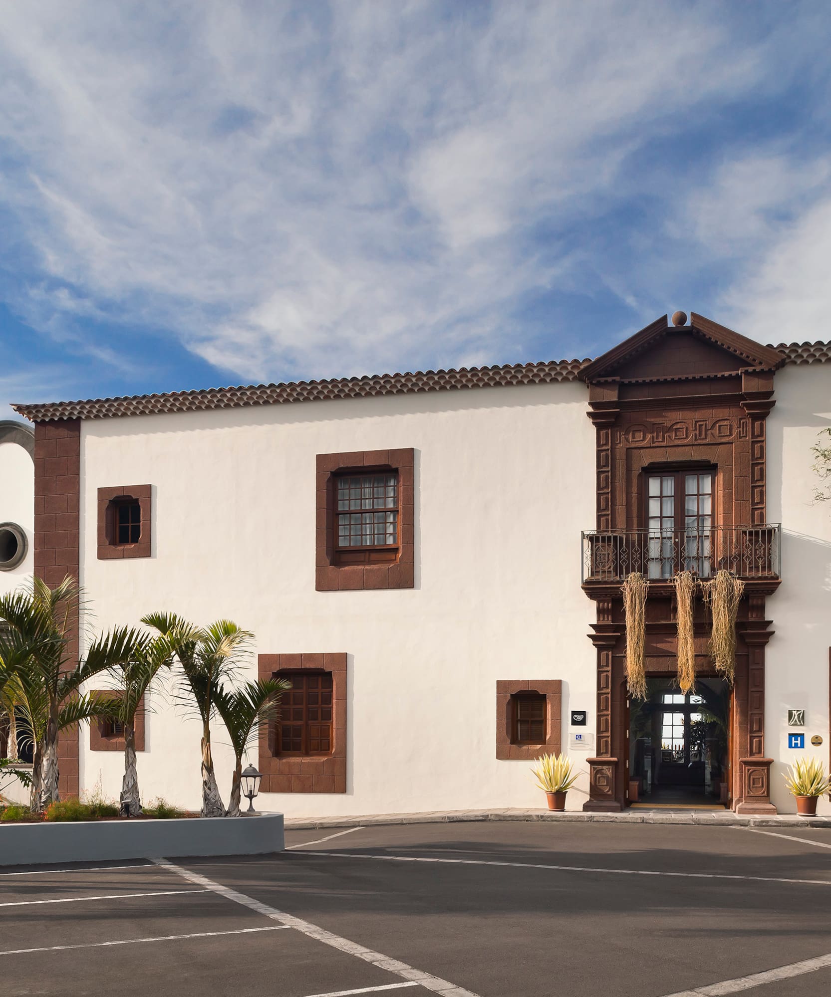 Historic hotel with bell tower, palm trees, and ornate brown facade.