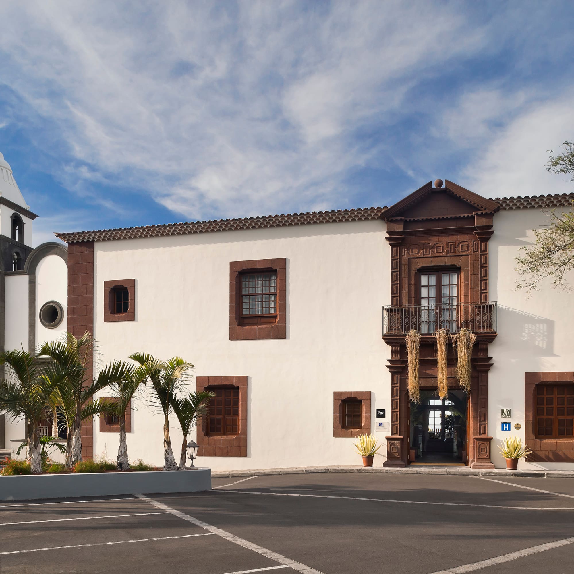 Historic hotel with bell tower, palm trees, and ornate brown facade.