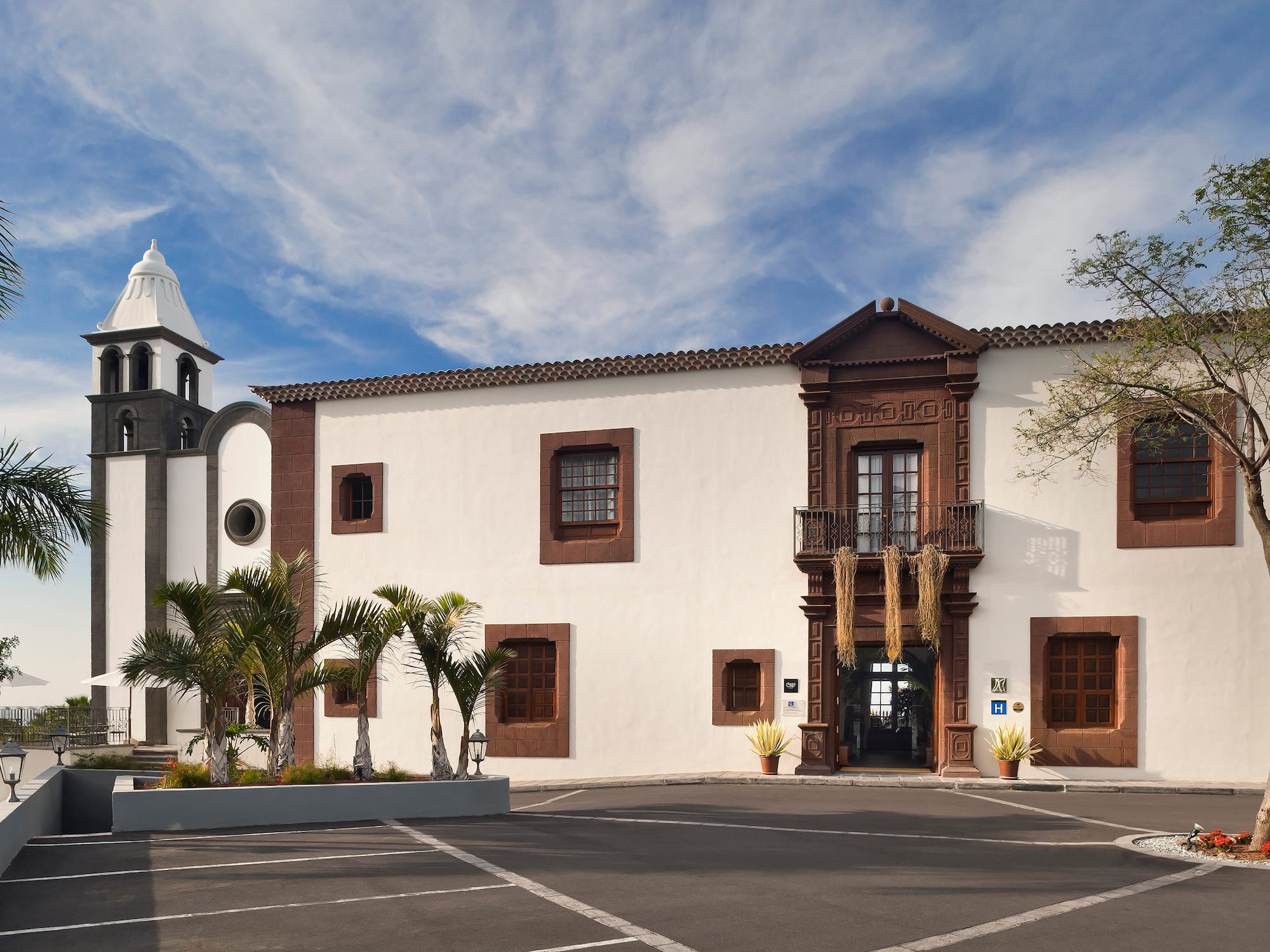 Historic hotel with bell tower, palm trees, and ornate brown facade.