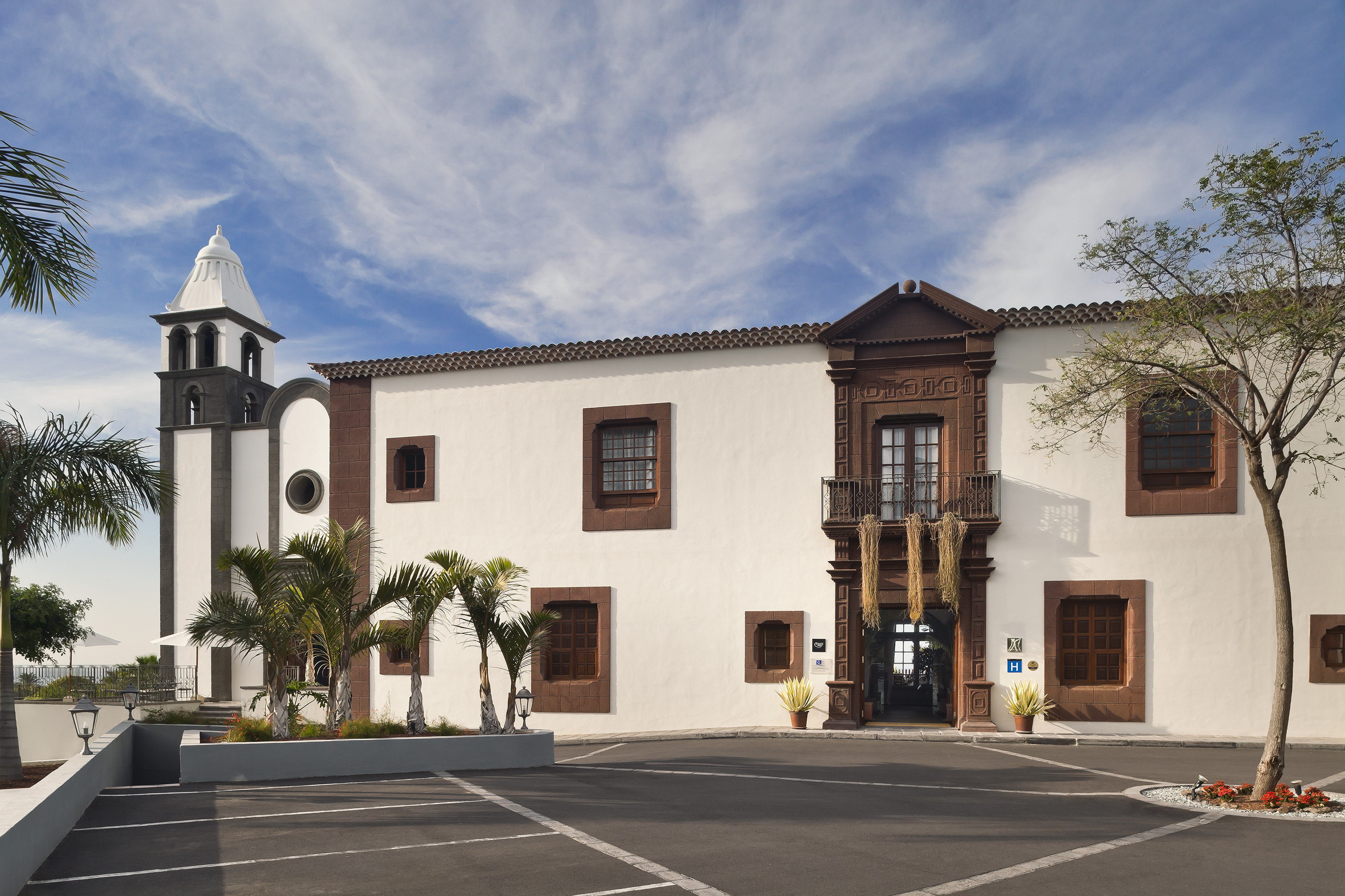 Historic hotel with bell tower, palm trees, and ornate brown facade.