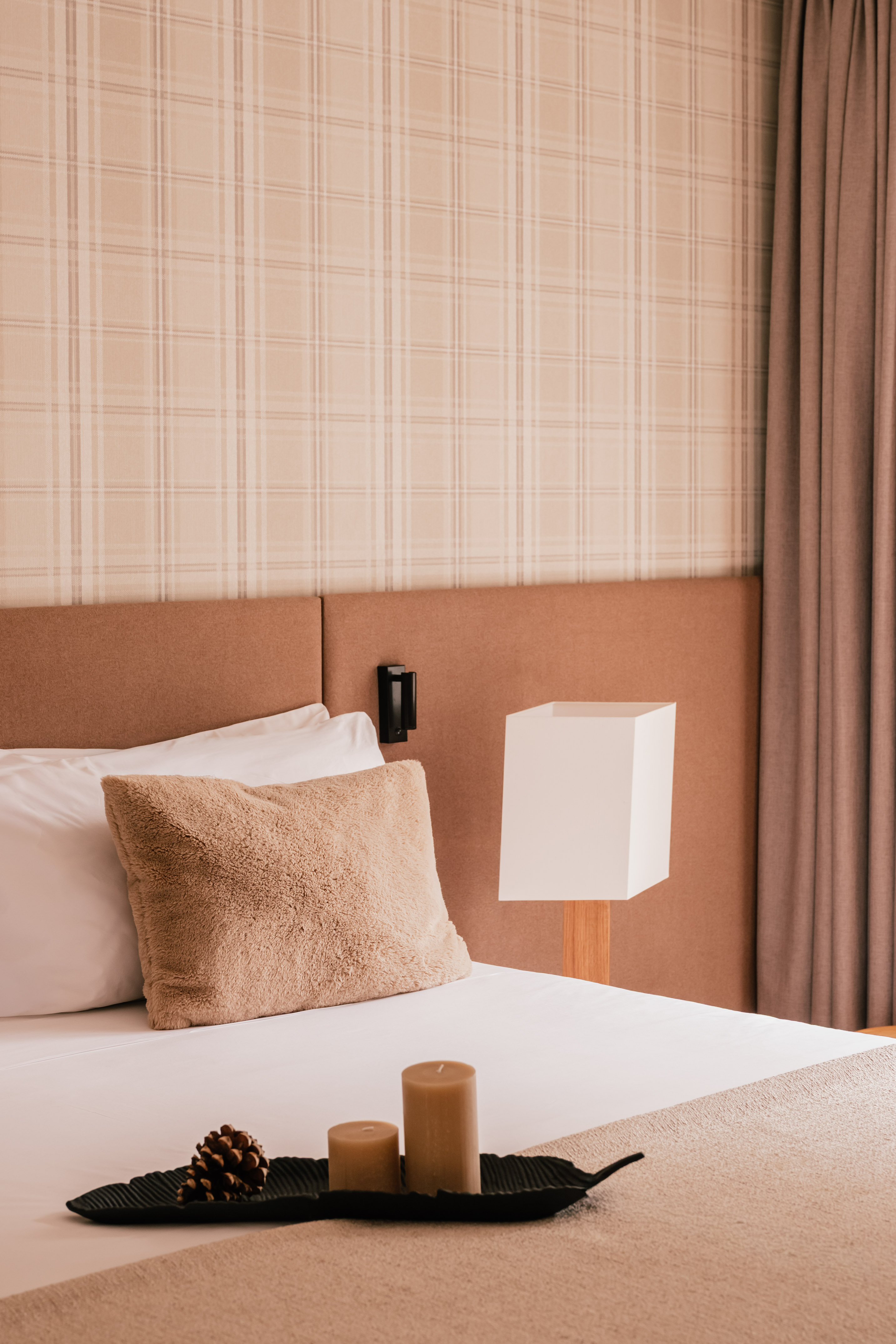 Cozy bedroom with plaid wallpaper, fluffy pillow, modern lamp, and natural decor.