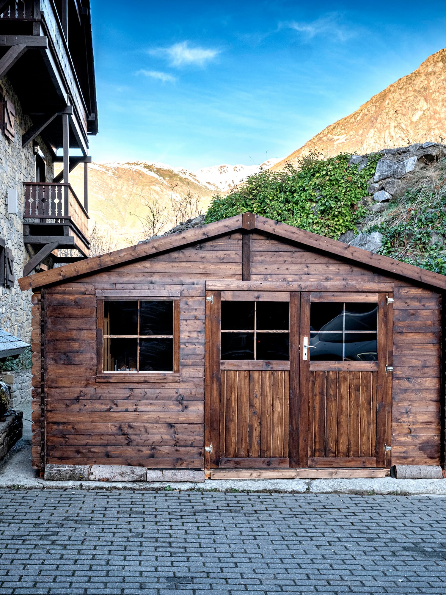 a wooden building with a stack of wood in front of a stone building