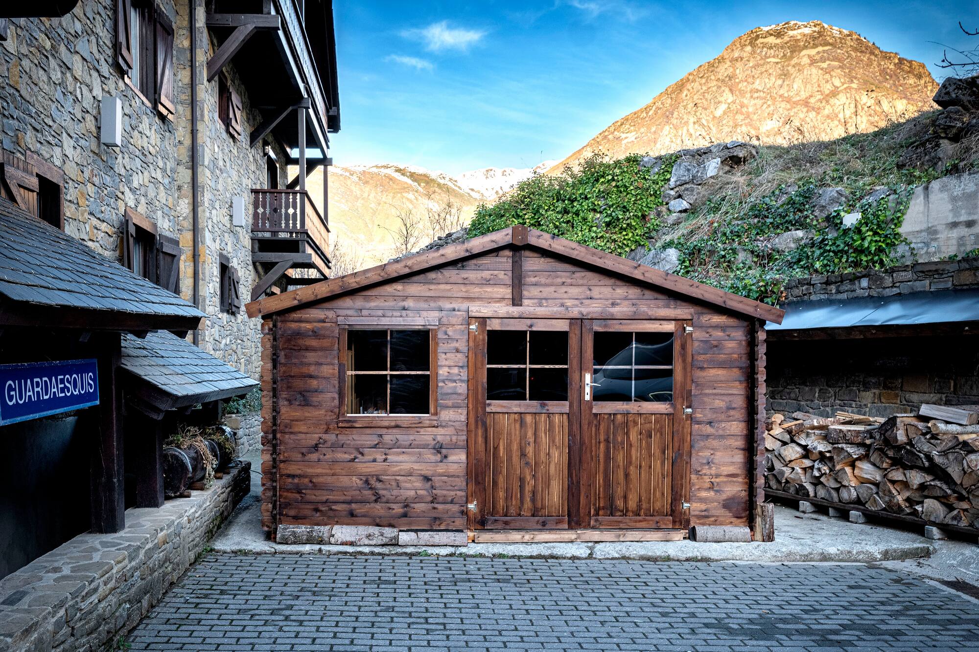 Wooden 'GUARDAESQUIS' ski storage shed in rustic mountain village.