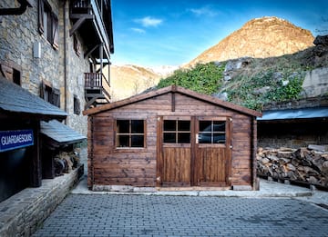 a wooden building with a stack of wood in front of a stone building
