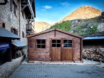 a wooden building with a stack of wood in front of a stone building