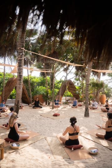 a group of people sitting in yoga mats on the sand