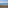 Paisaje costero: muro de piedra seca, hierba, mar azul y cielo.