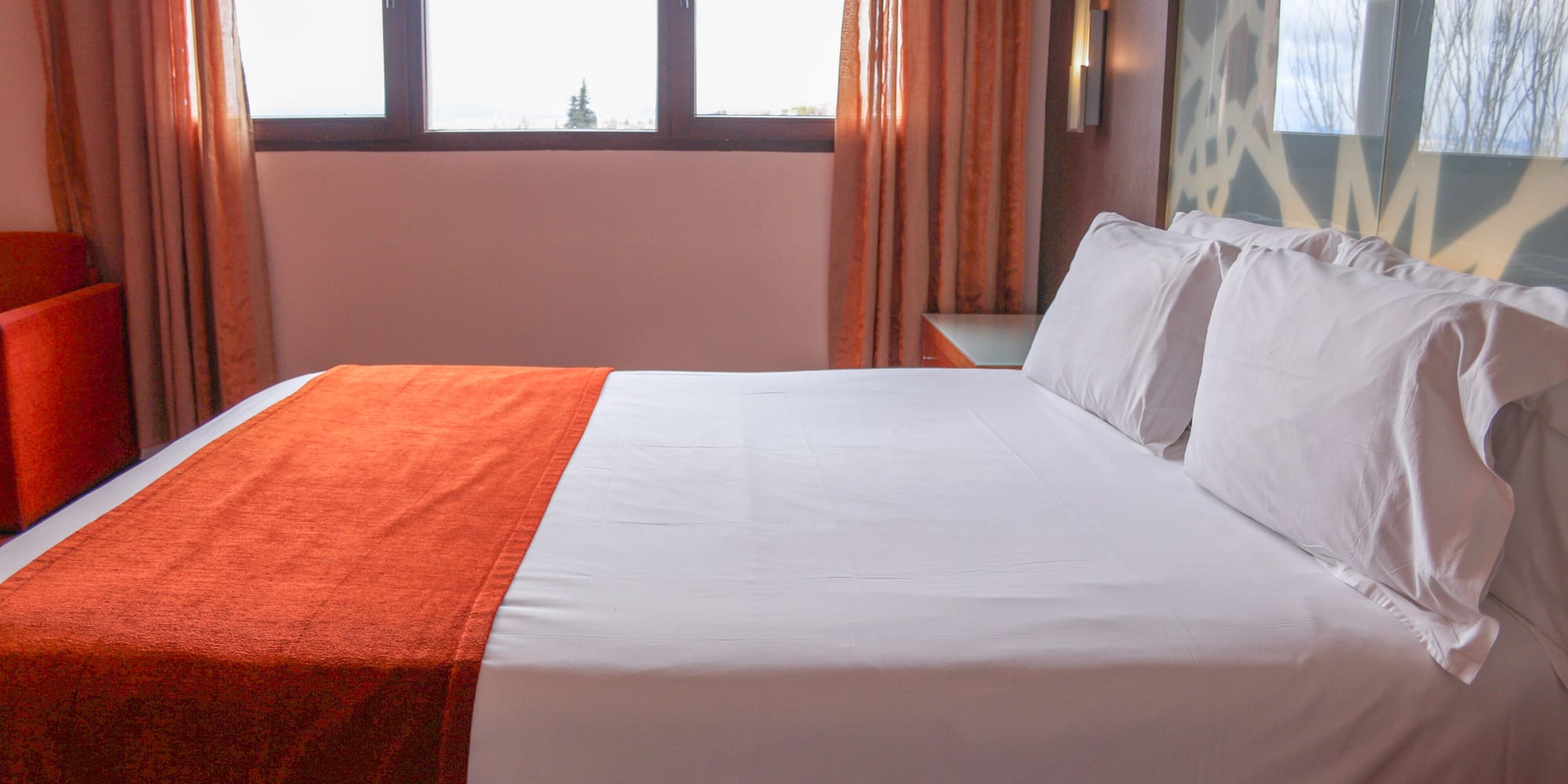 a bed with orange blanket and pillows