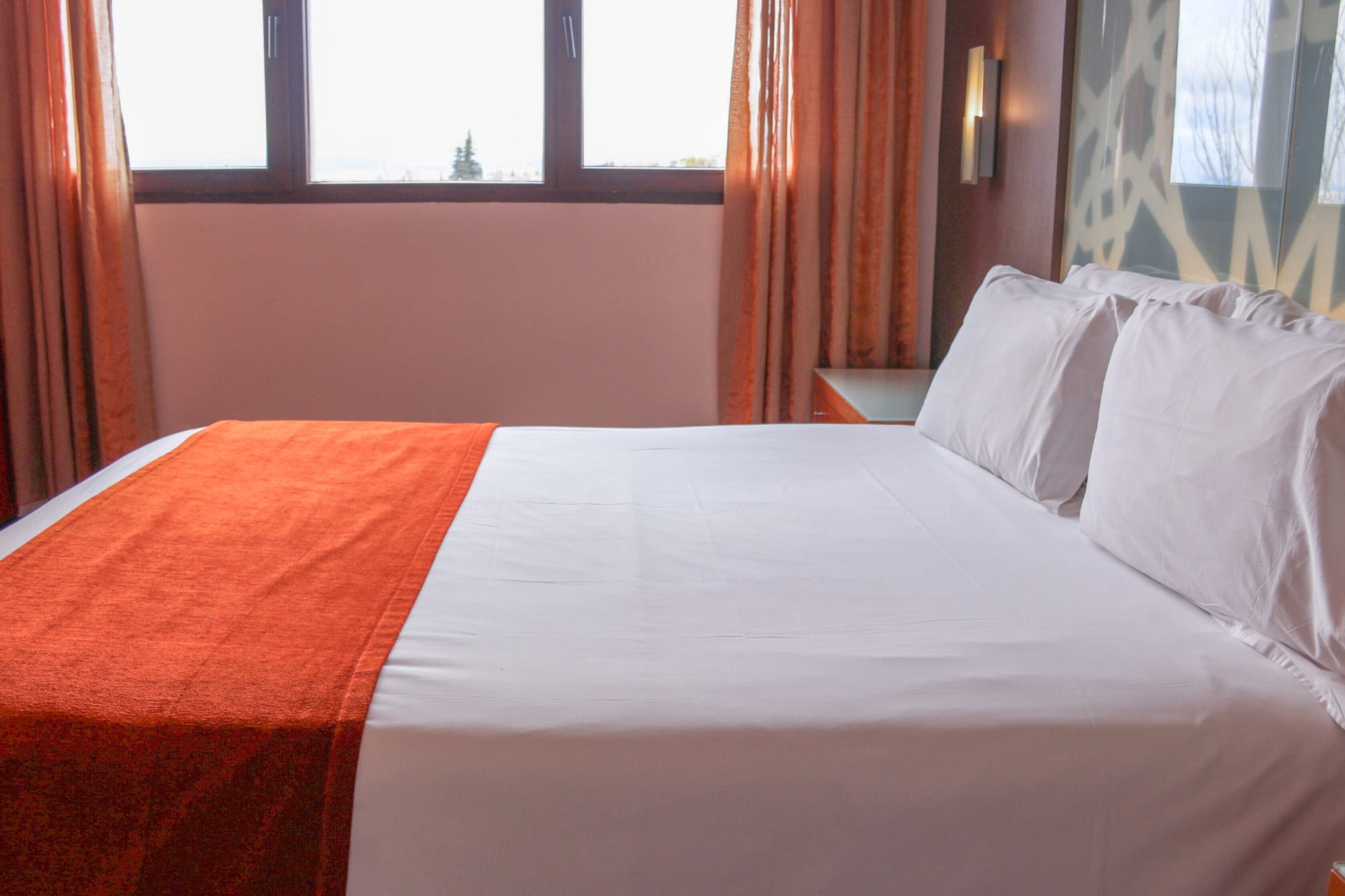 a bed with orange blanket and pillows