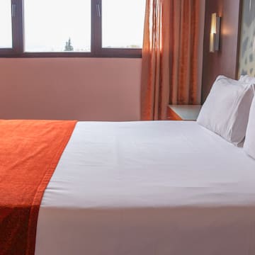 a bed with orange blanket and pillows