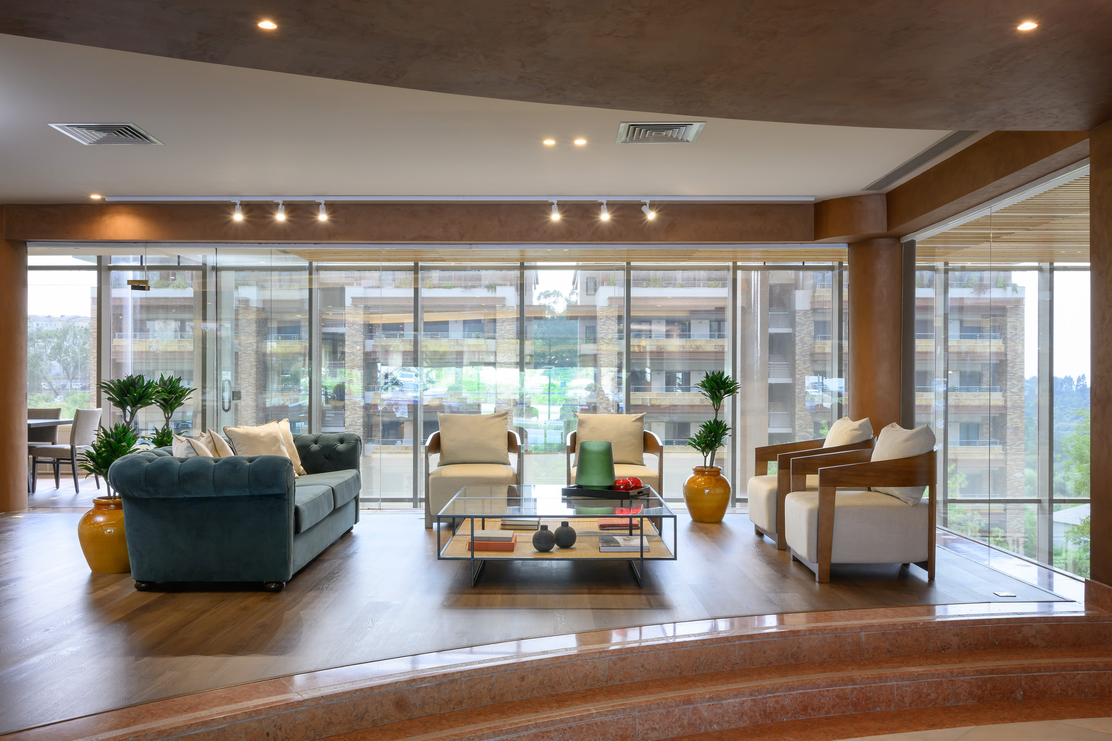 Luxury modern lounge with large windows, teal sofa, and elegant seating.