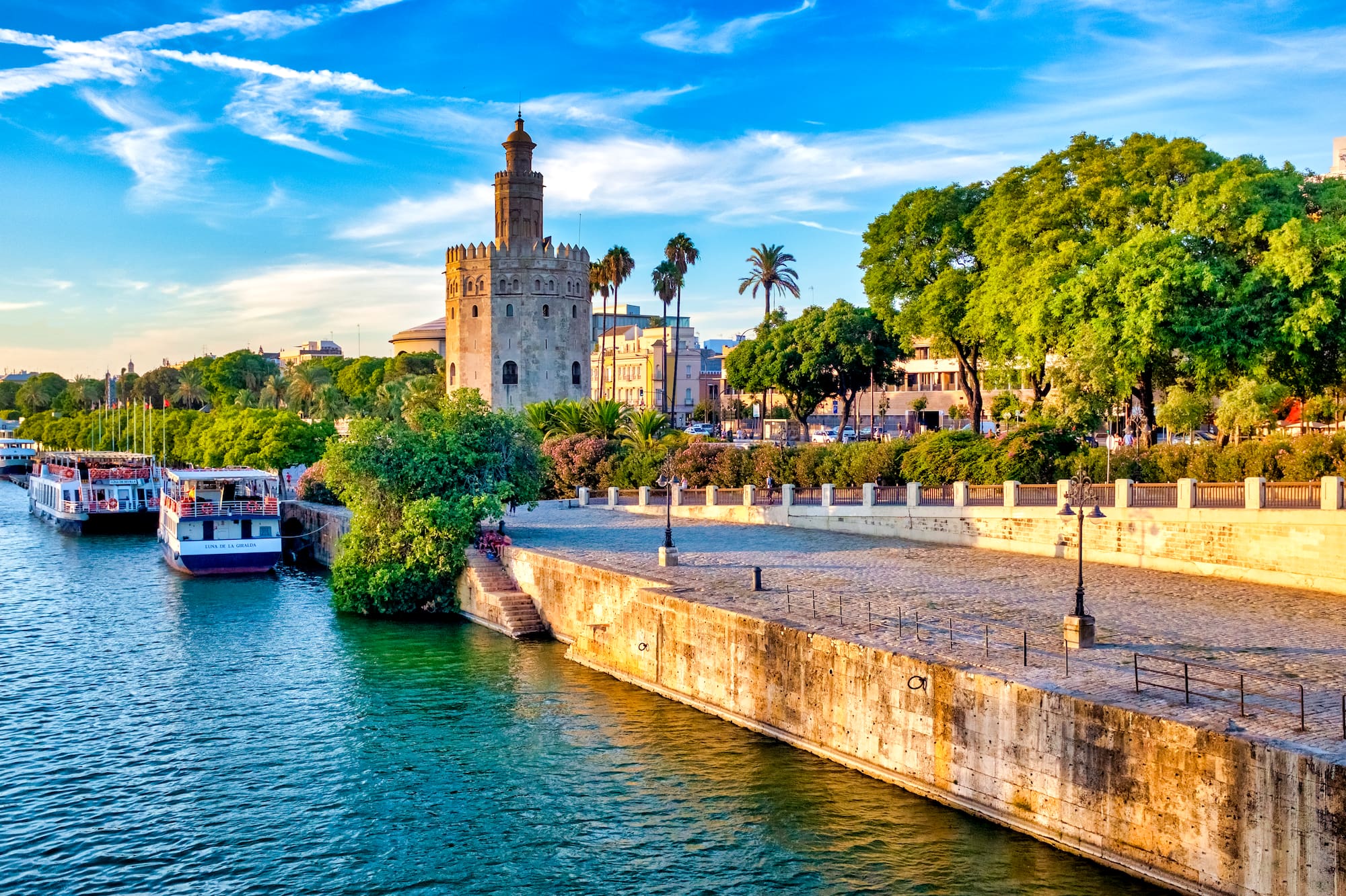 Seville's Torre del Oro on Guadalquivir River with tour boats.