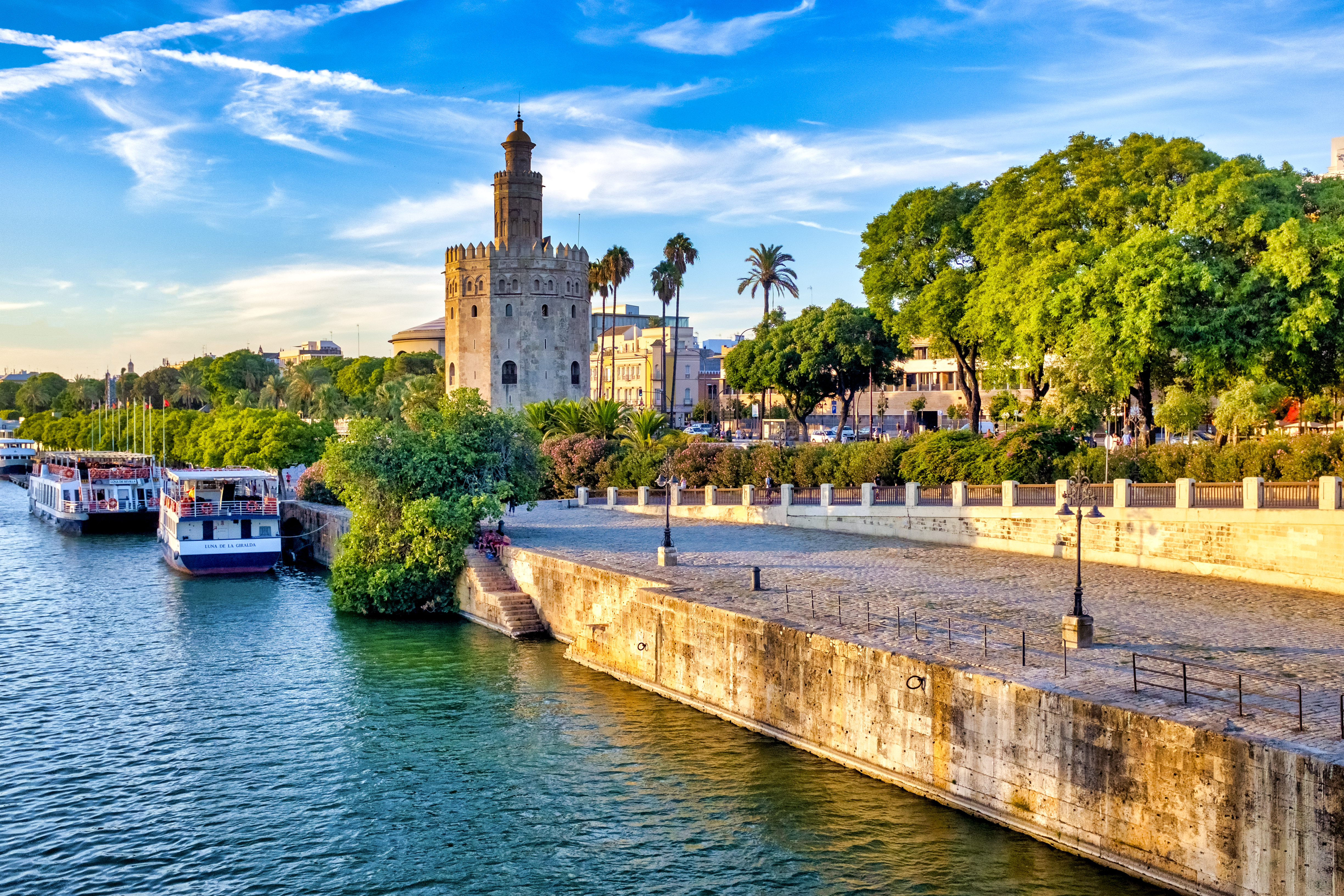 Seville's Torre del Oro on Guadalquivir River with tour boats.