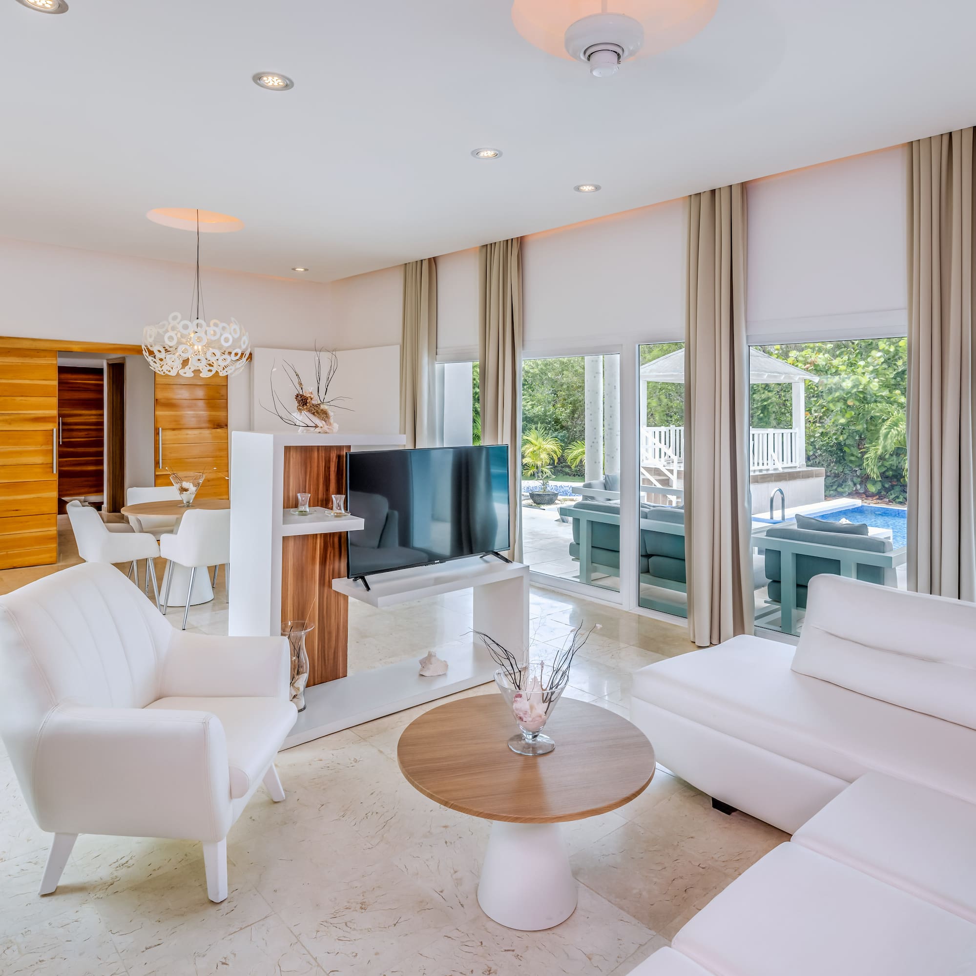 a living room with white furniture and a television