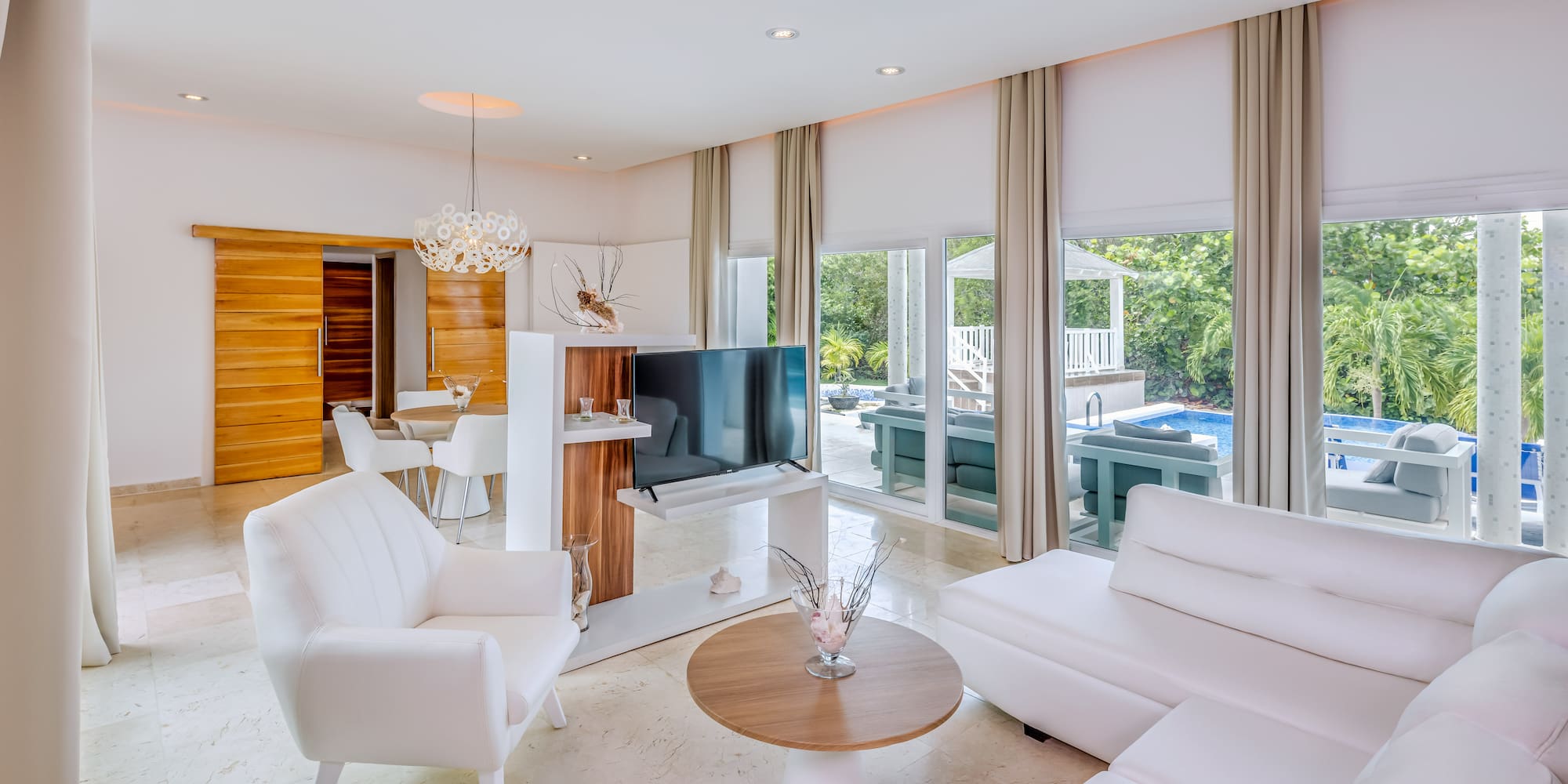 a living room with white furniture and a television