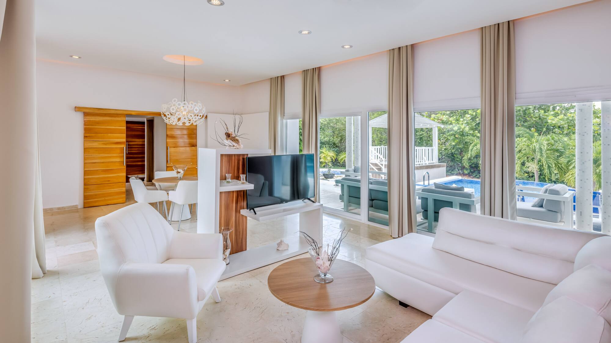 a living room with white furniture and a television