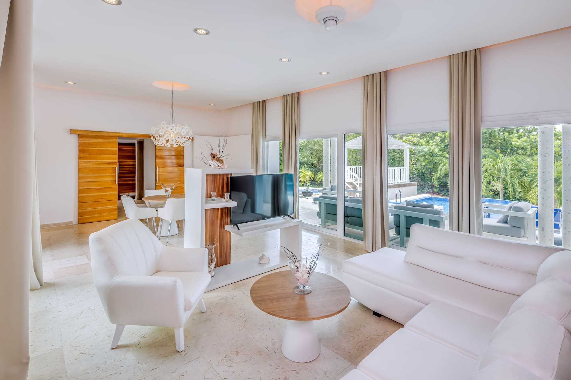 a living room with white furniture and a television