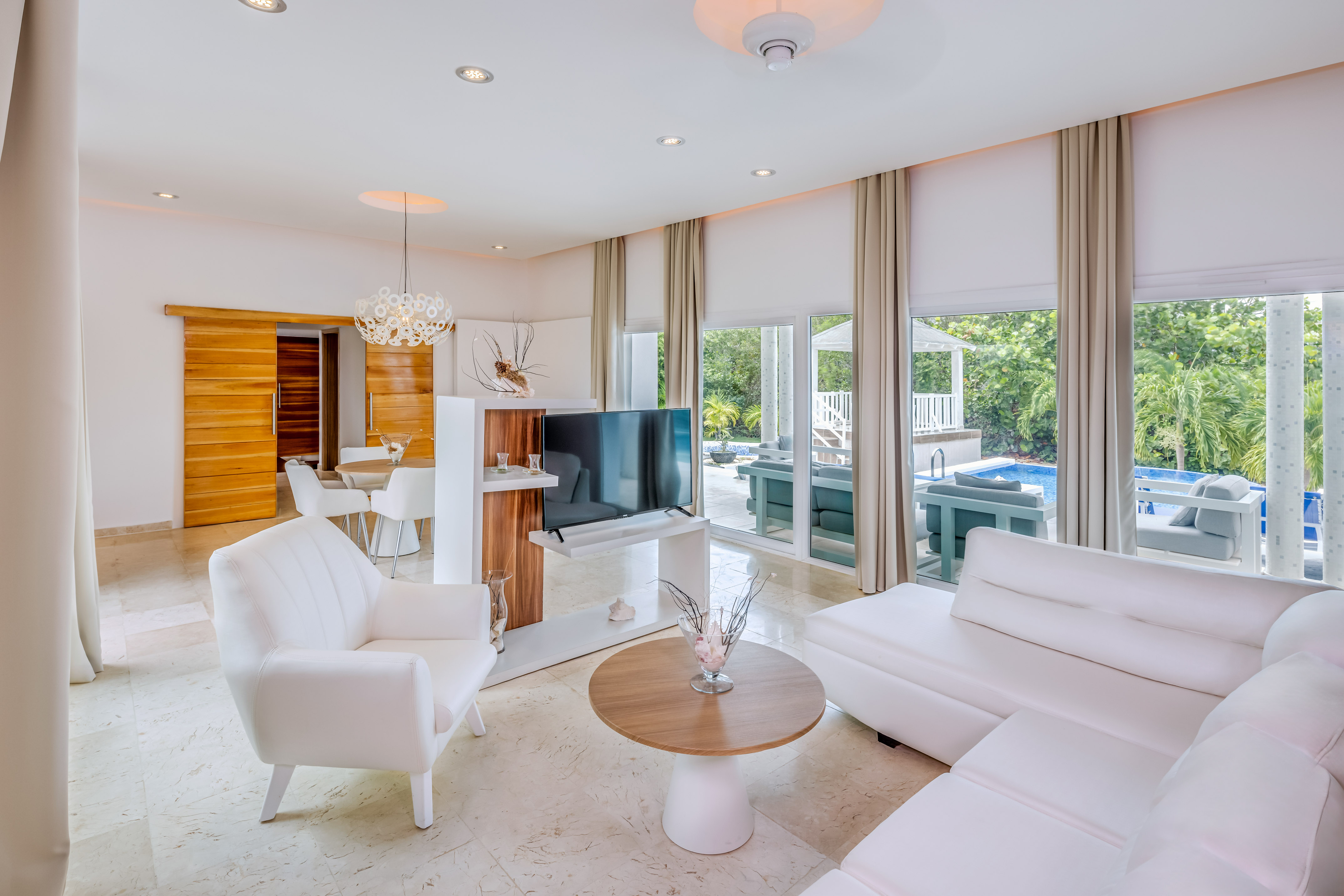 a living room with white furniture and a television