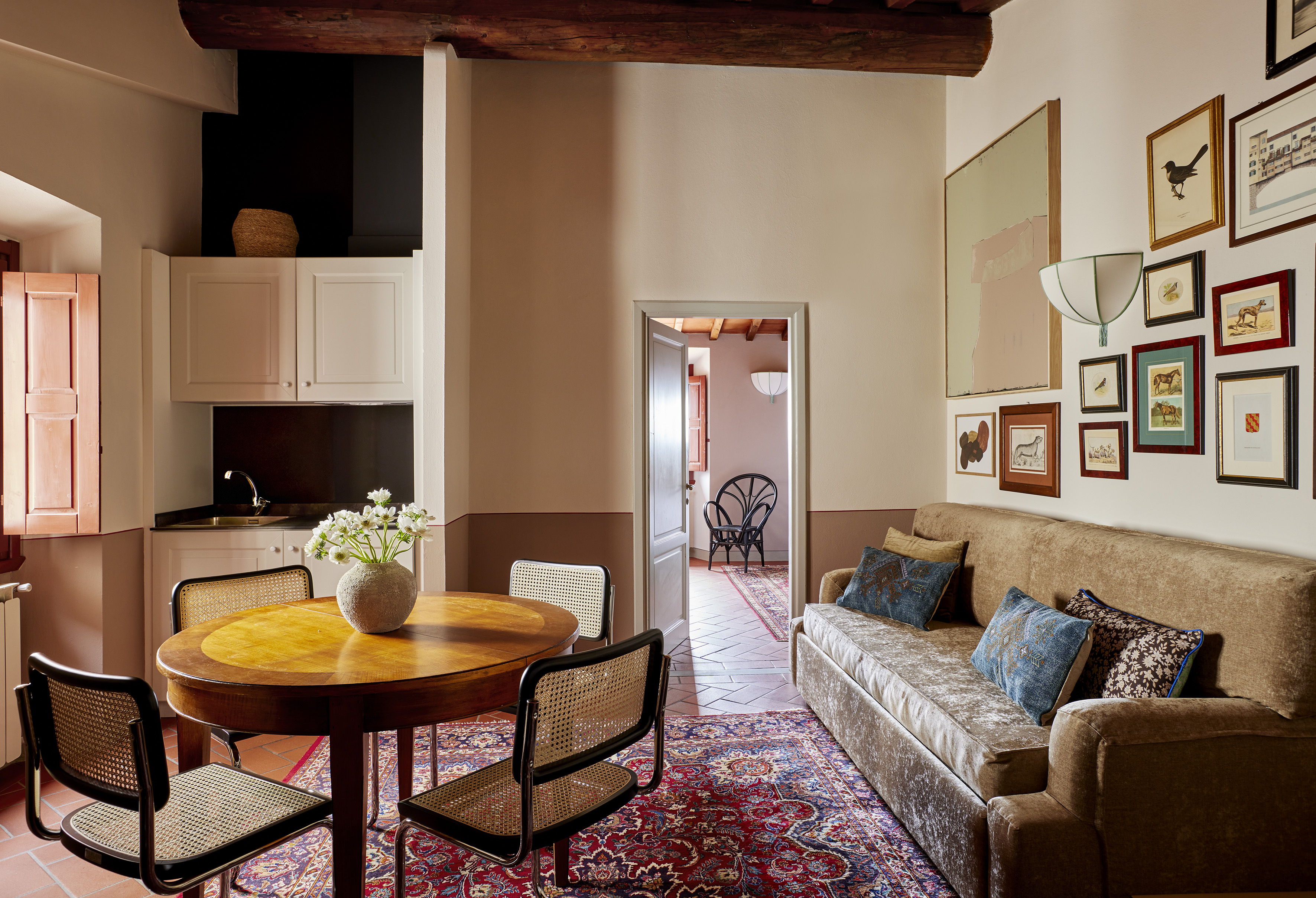 Cozy apartment living room with dining table, velvet sofa, and gallery wall art.