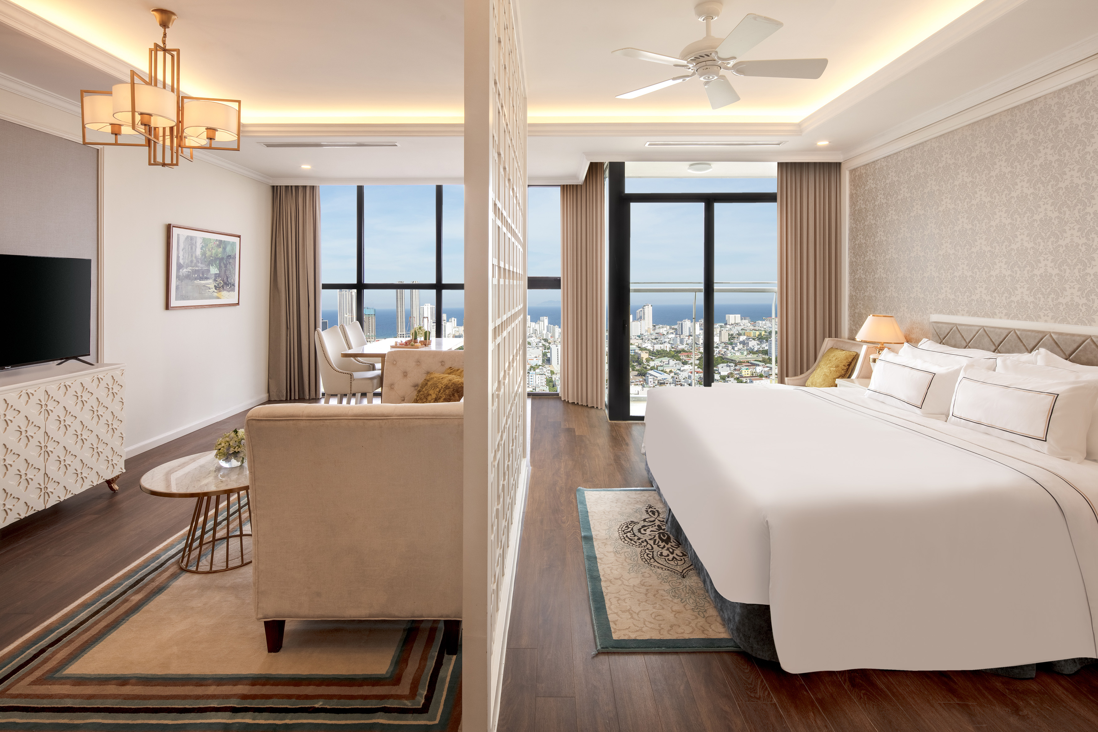 Luxury hotel suite with separate living, bedroom, dining, and ocean city view.