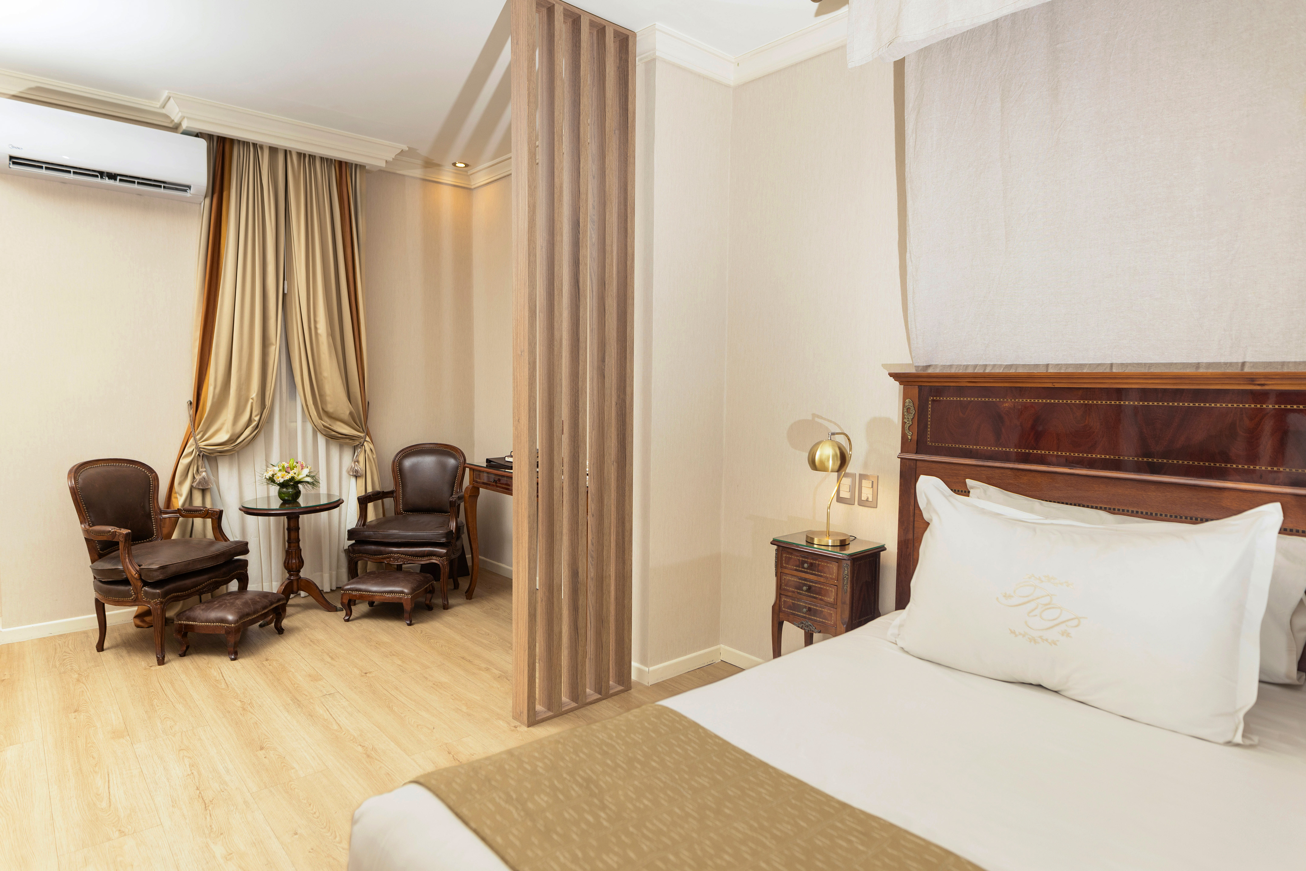 Elegant hotel suite with bedroom, sitting area, and stylish wooden partition.