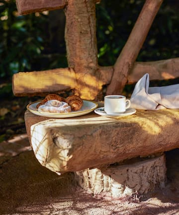 a plate of pastries and a cup of coffee on a stone bench