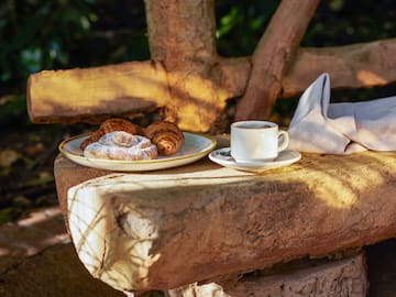 a plate of pastries and a cup of coffee on a stone bench