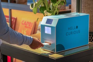 a person's hand pressing a paper into a machine