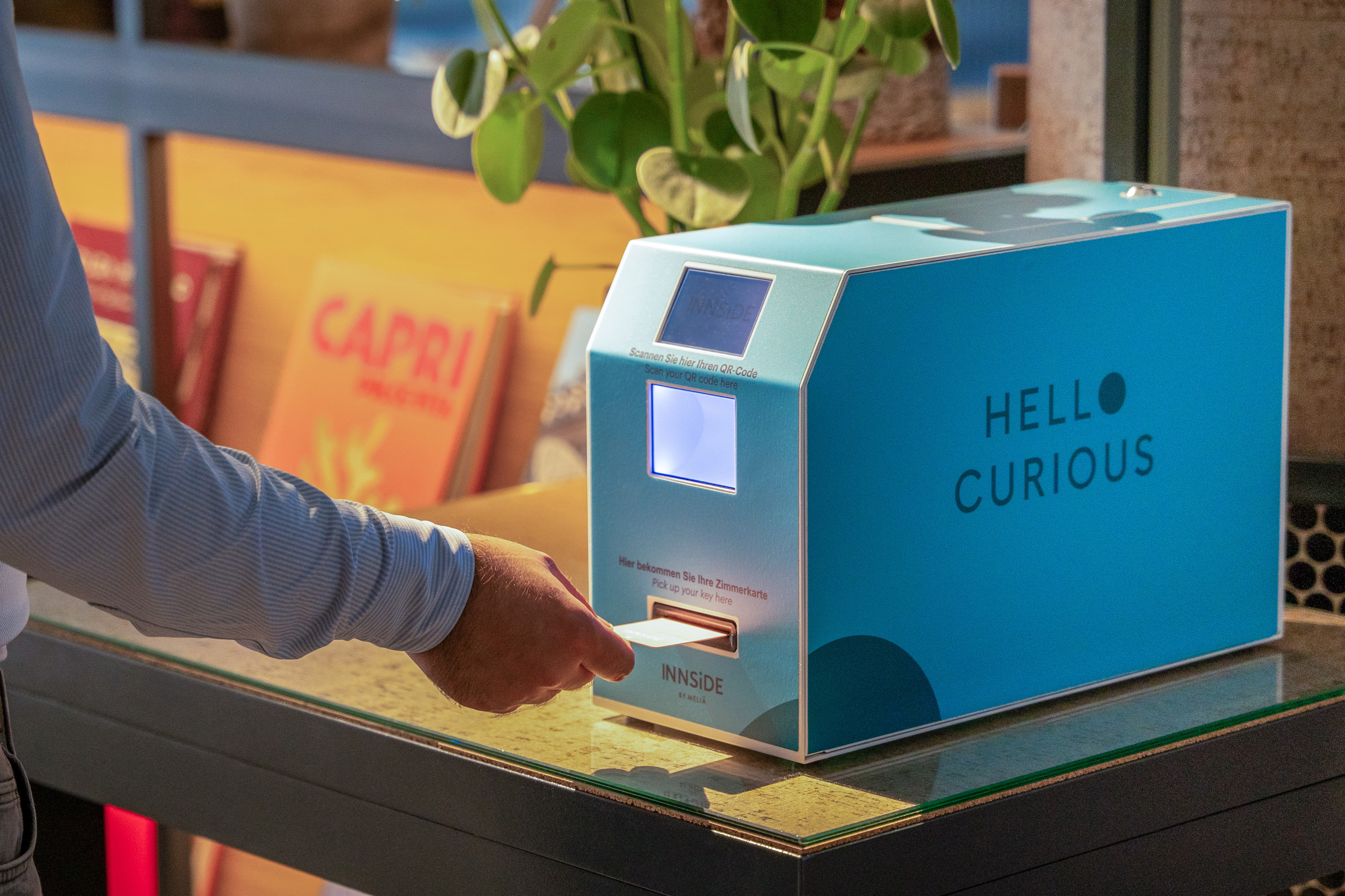 Person retrieving hotel key card from INNSIDE self-service kiosk.