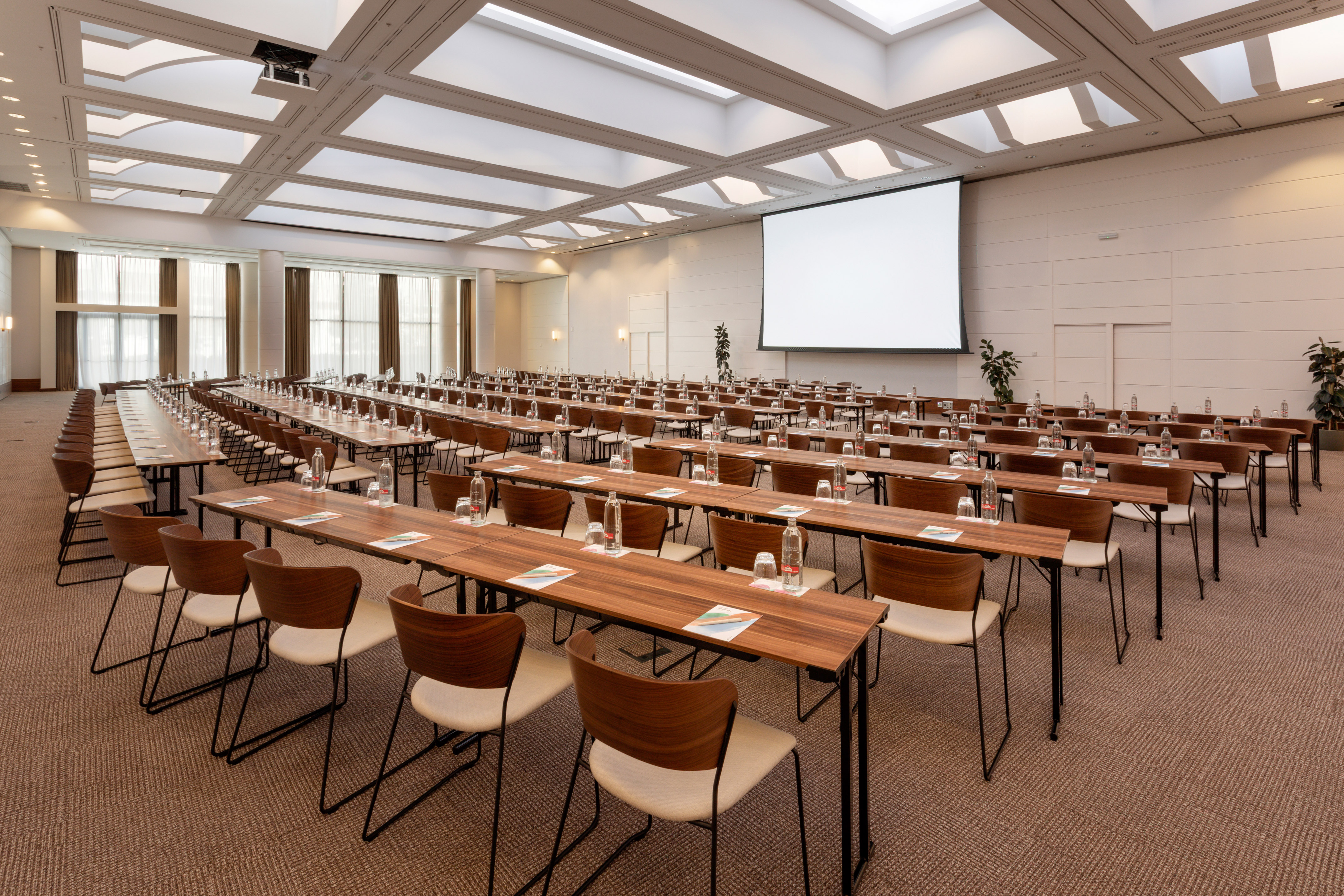 Conference room with classroom setup, wooden tables, and projector screen.