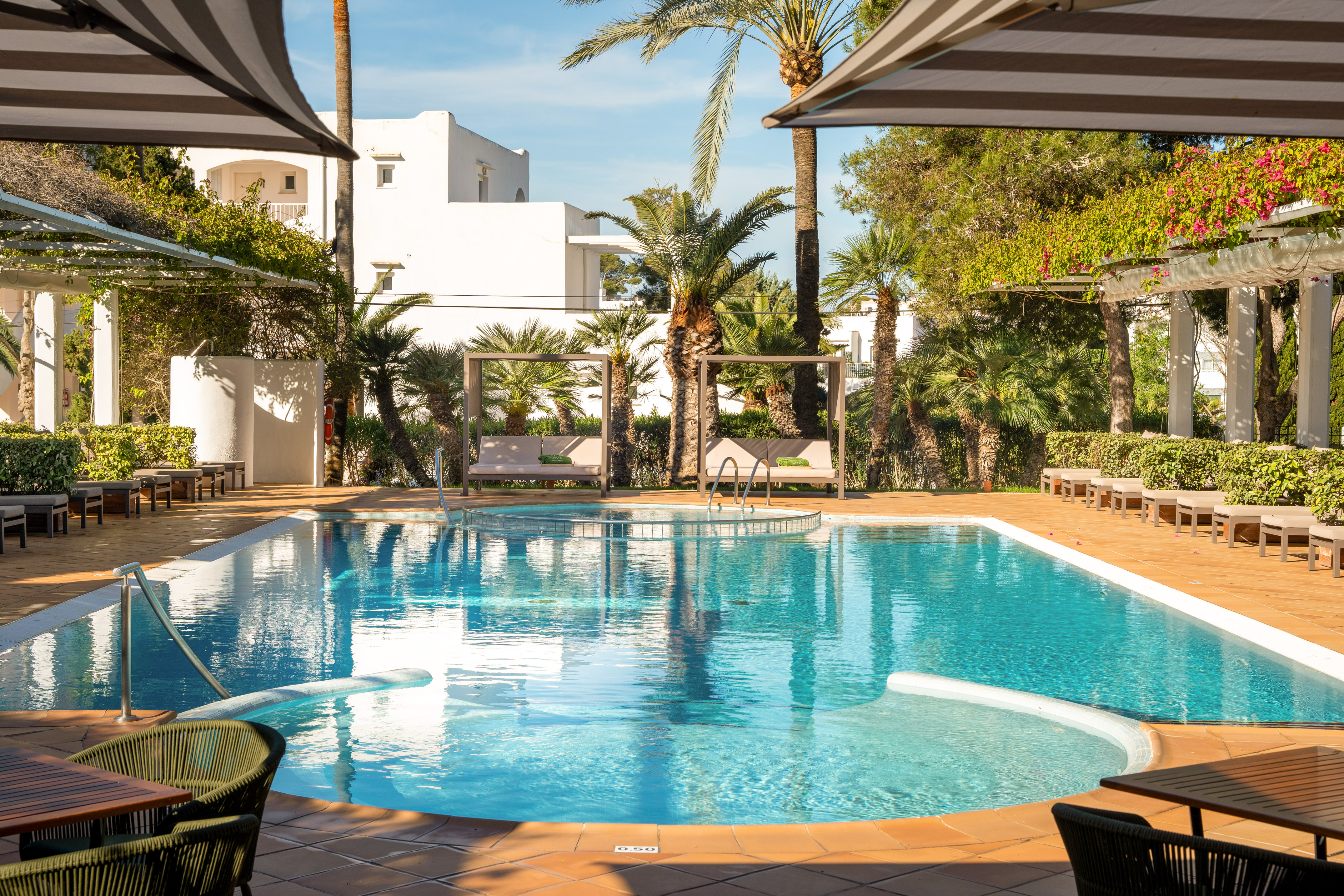 Tropical resort pool with cabanas, palm trees, and elegant patio.