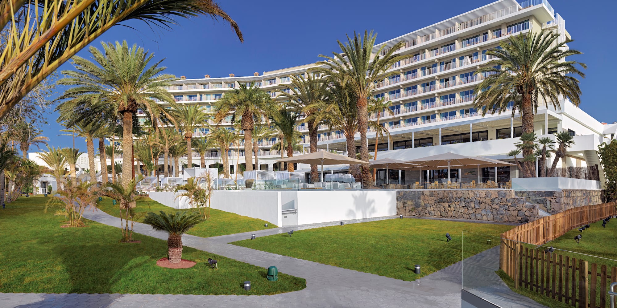 a large building with palm trees and a lawn