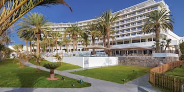 a large building with palm trees and a lawn