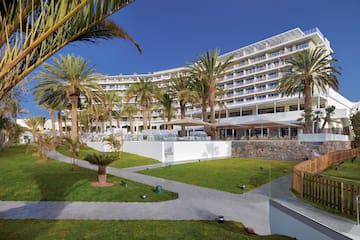 a large building with palm trees and a lawn