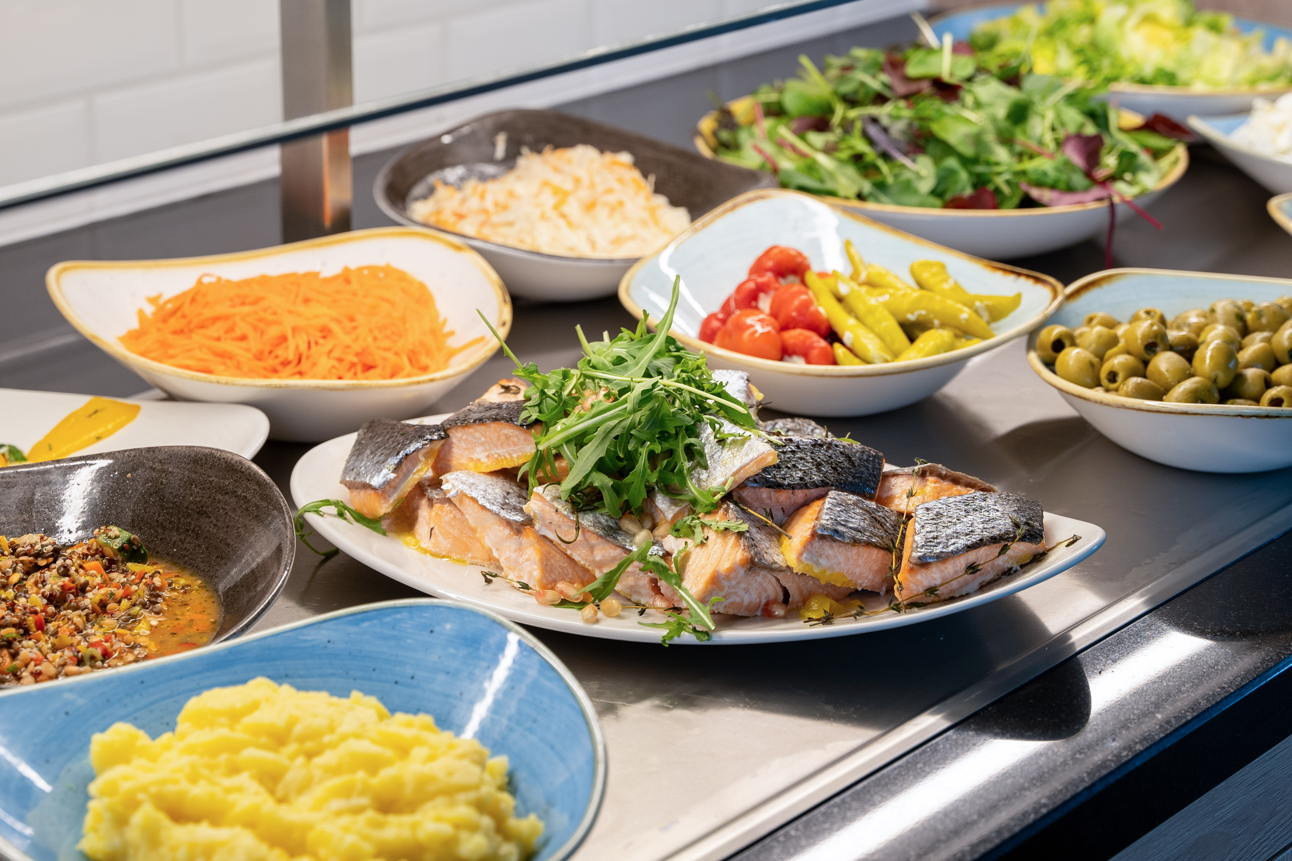 Assorted buffet spread with salmon, mashed potatoes, salads, and olives.