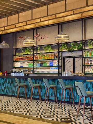 a bar with bottles of drinks and chairs