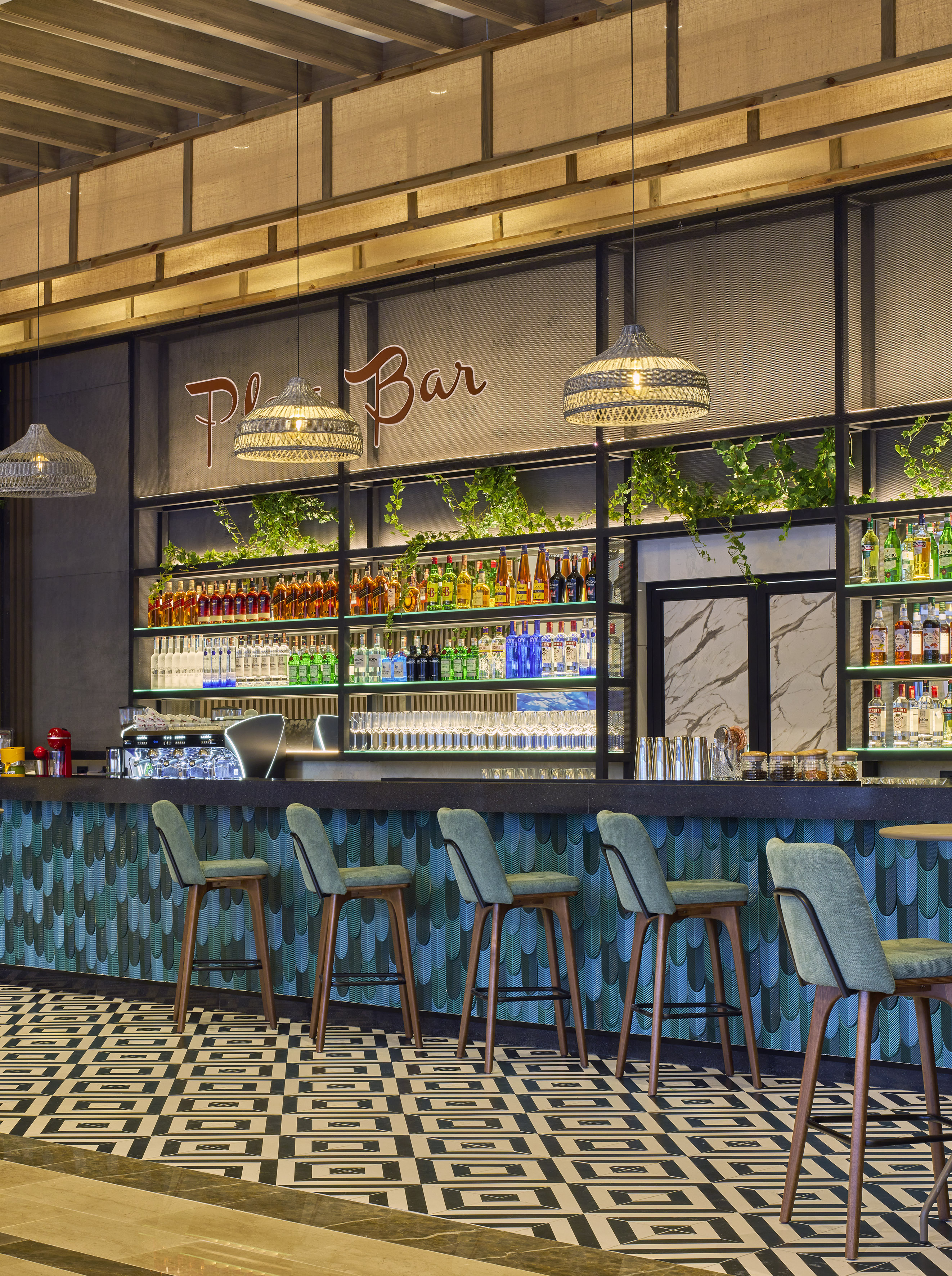 Modern bar with 'Play Bar' sign, teal counter, liquor display, and green stools.