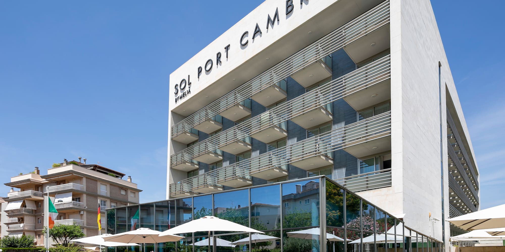 a building with a glass wall and a lawn with tables and chairs