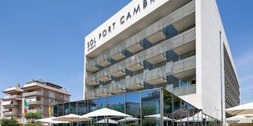 a building with a glass wall and a lawn with tables and chairs
