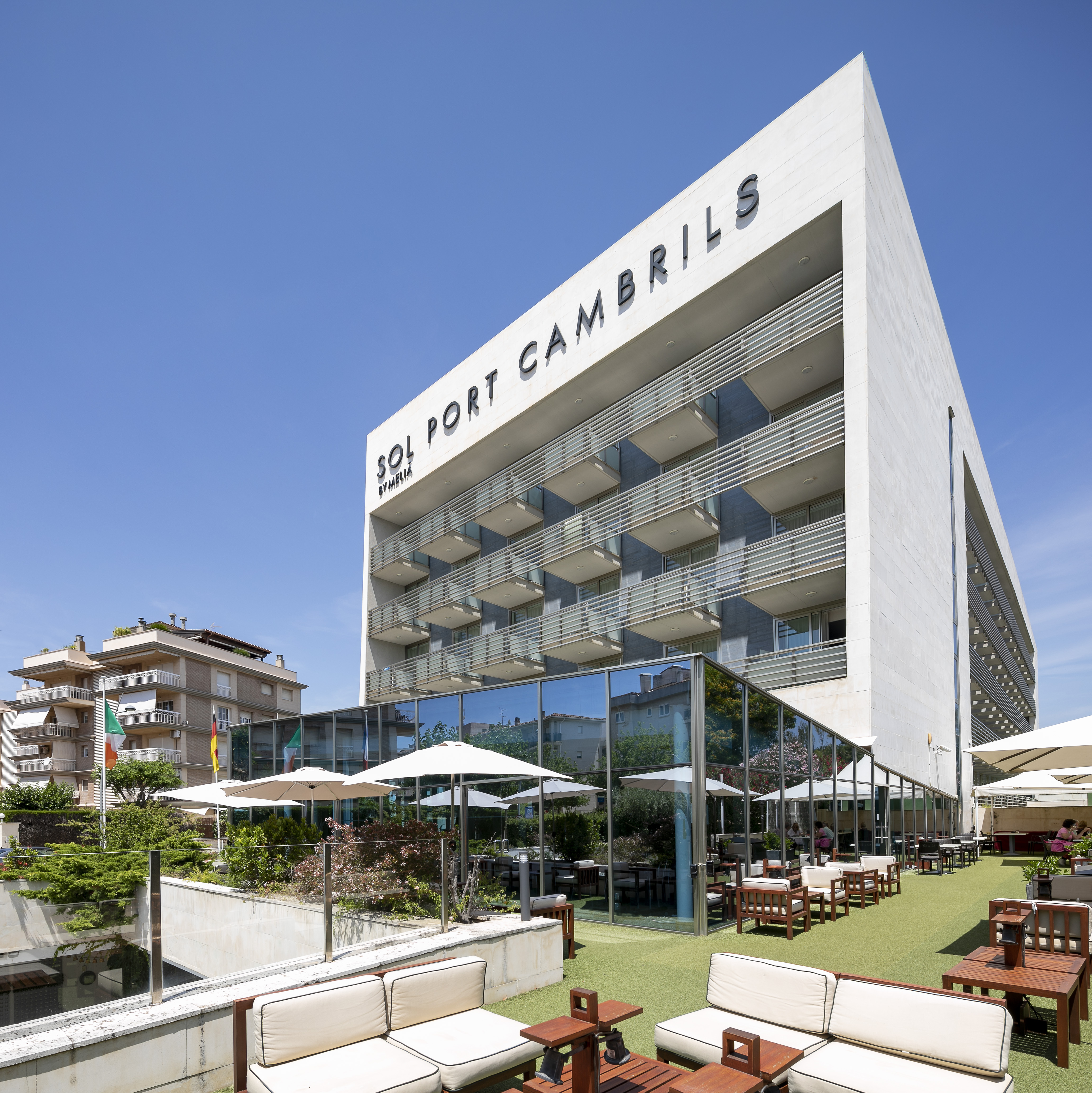 a building with a glass wall and a lawn with tables and chairs