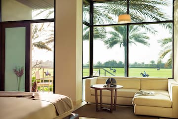 a room with a bed and couches and a table with chairs and a golf course