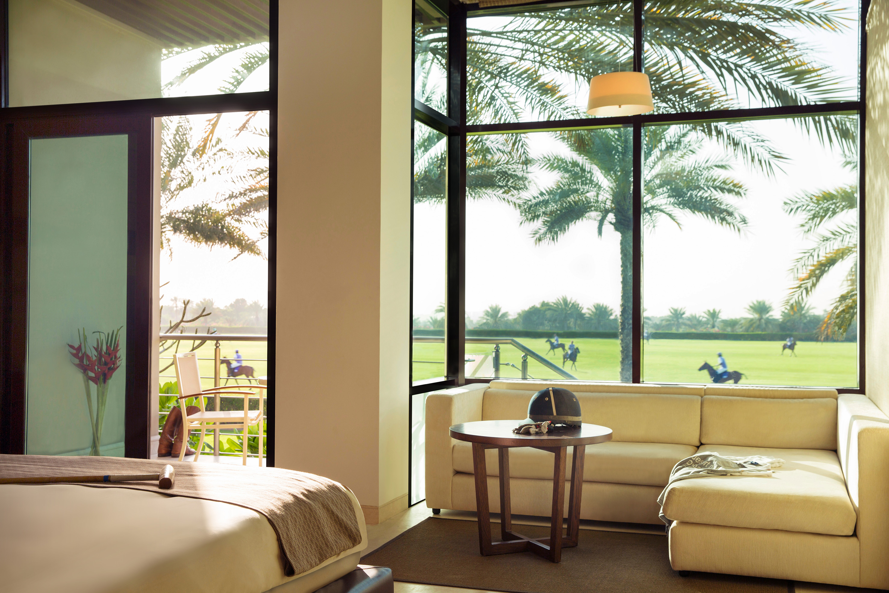 Elegant room with polo field view, riders, palm trees, and polo gear.