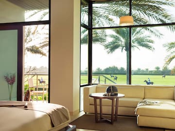 a room with a bed and couches and a table with chairs and a golf course